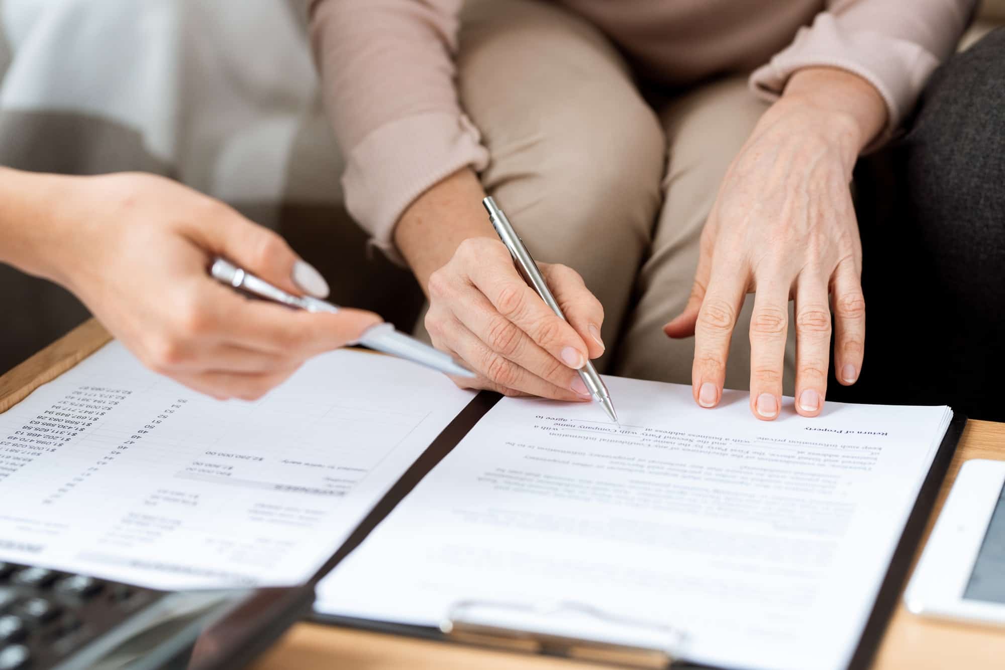 Hands of mature client and real estate agent with pens pointing at contract